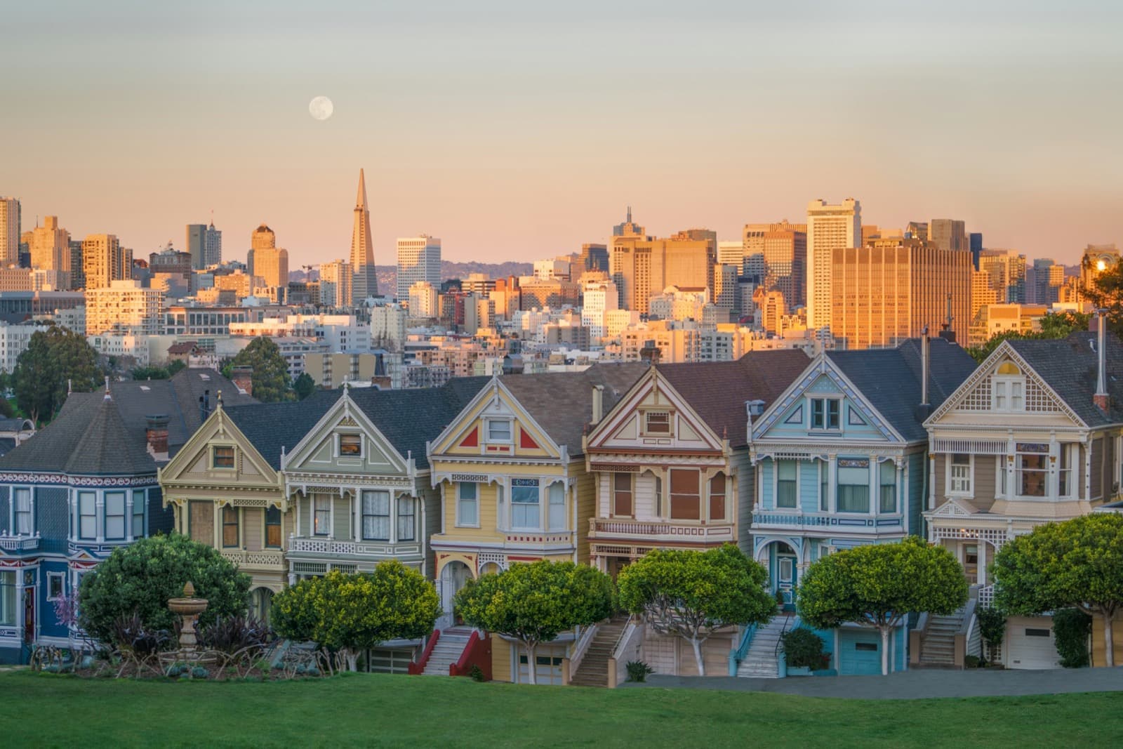 The Painted Ladies Victorians at Alamo Square with the San Francisco skyline and a rising moon at sunset
