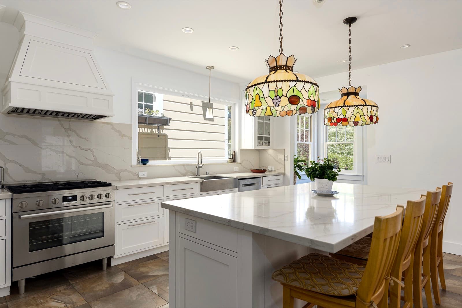 The rebuilt kitchen: the range under its custom plaster hood, marble backsplash and counters, with the new island alongside