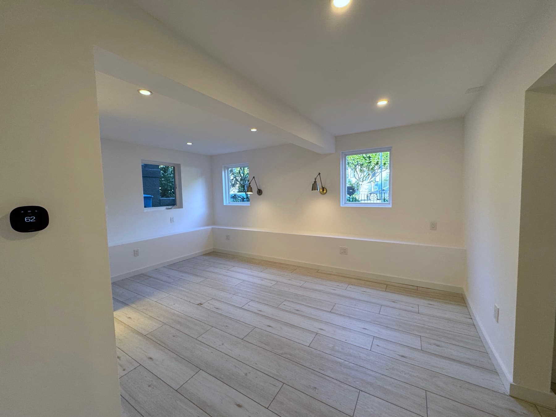 The bedroom finished, two new windows and their sconces, the floor running the width of the room