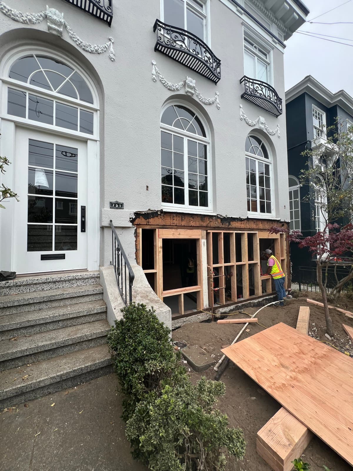 The front of the house during the work, the lower level opened to bare framing beside the entry steps