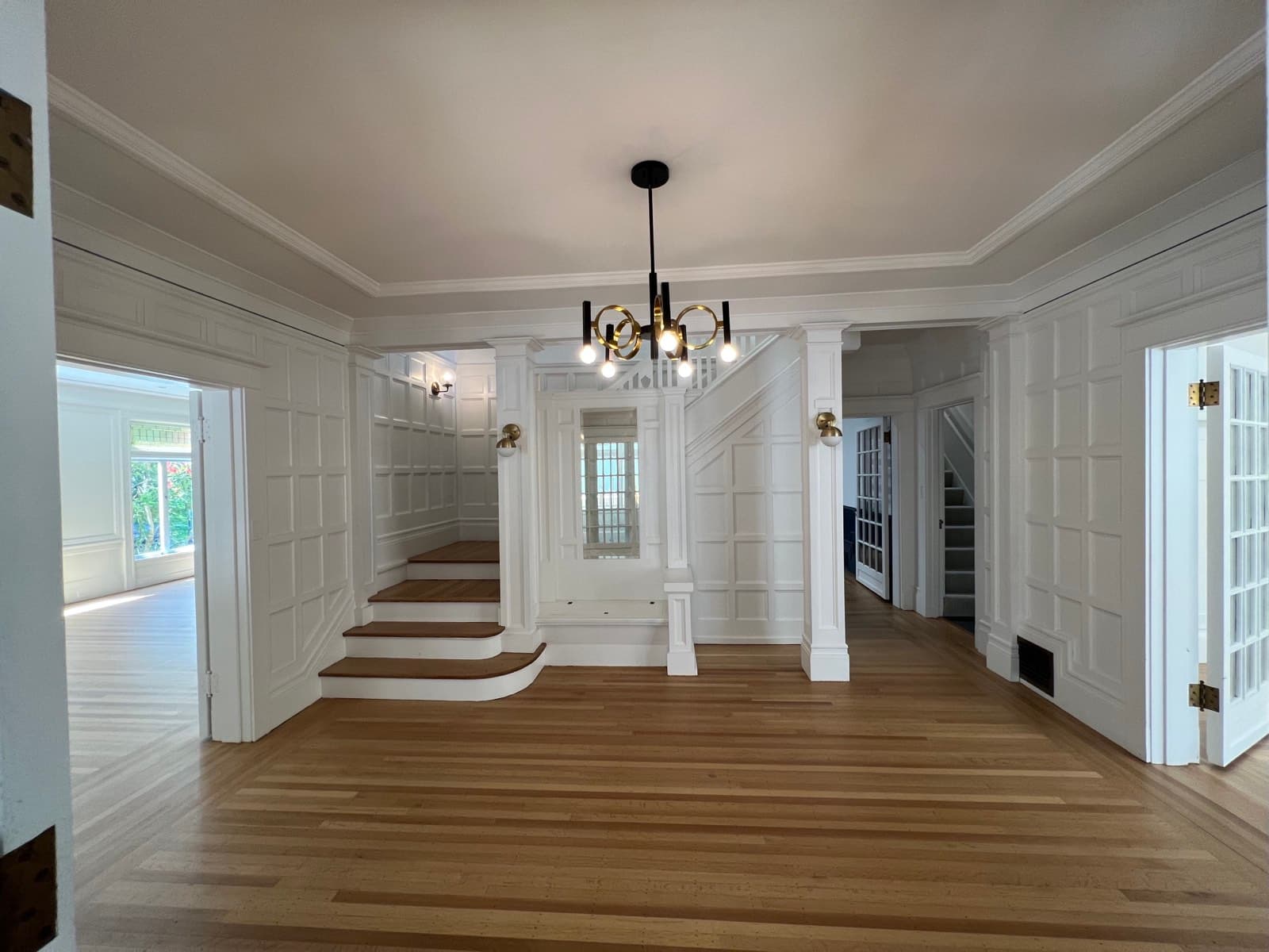 Entry hall with paneling, columns and staircase painted entirely white, as purchased