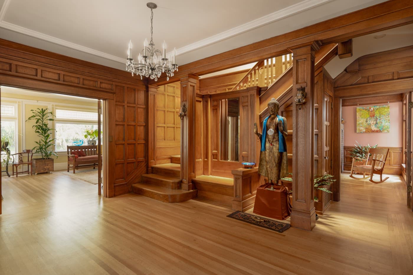 Entry hall with restored wood paneling and a chandelier