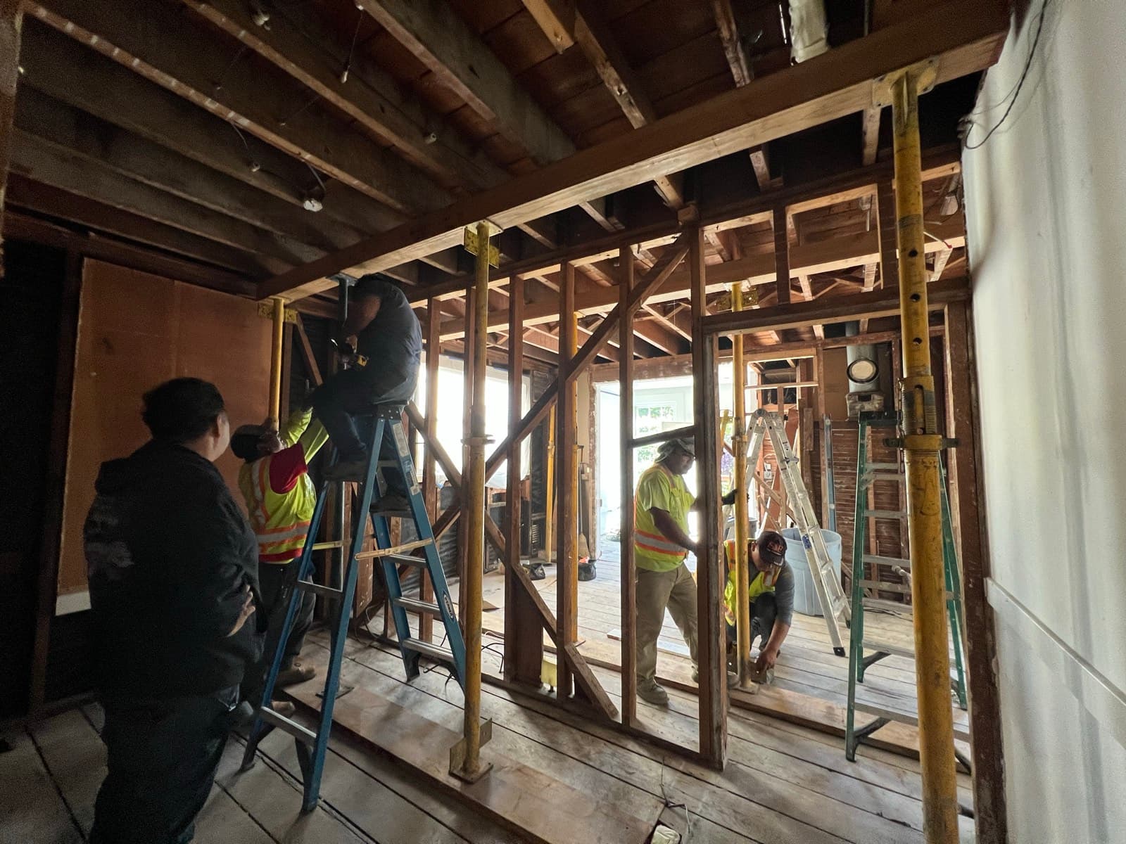 The crew setting the steel beam that now carries the kitchen ceiling, temporary shoring posts holding the span