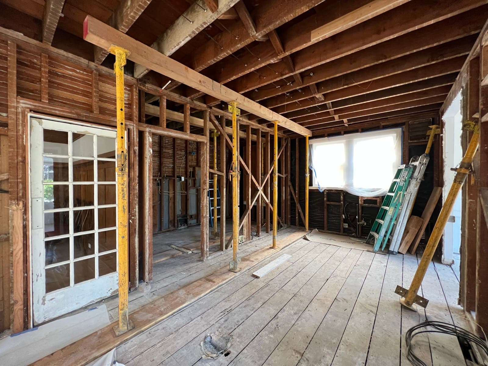 The opened span with the beam in place, original board sheathing exposed and the french doors still standing at left